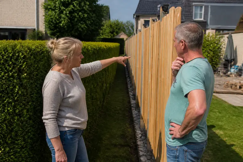Nachbarn besprechen die Höhe eines neuen Gartenzauns an der Grundstücksgrenze unter Einhaltung deutscher Vorschriften.