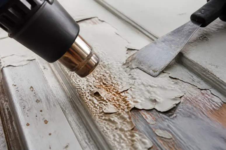 Heißluft föhnt Farbe auf Holz auf, die bereit ist, abgekratzt zu werden.