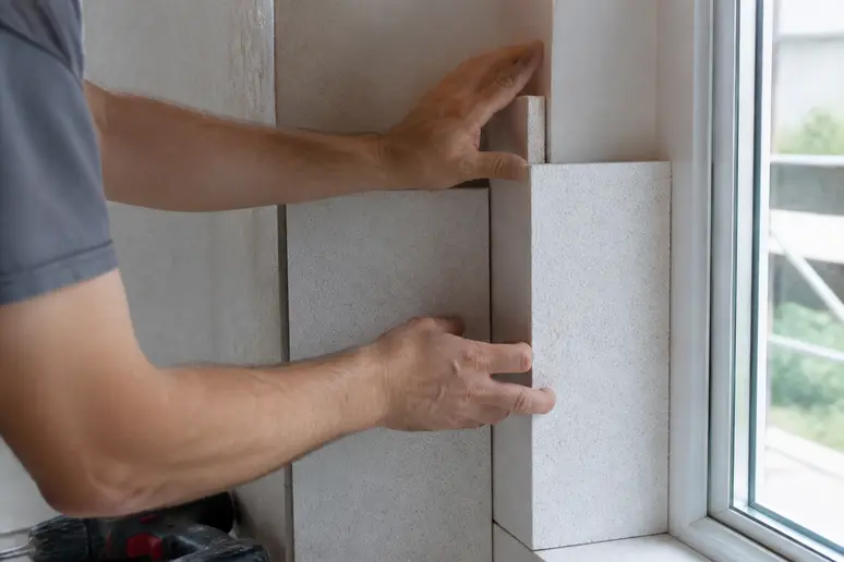 Präzise Anbringung von Kalziumsilikatplatten an einer Fensterlaibung durch Handwerker.