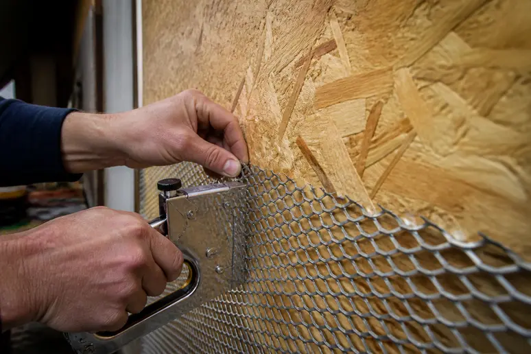 Anbringen eines Metallputzträgers auf OSB-Platten mit Krampen für stabile Oberflächen.