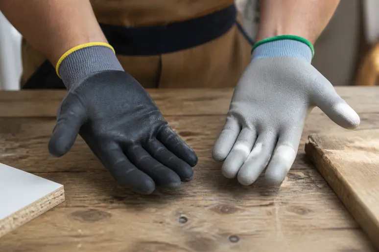 Schutzhandschuhe für Renovierungsarbeiten aus Nitril und PU im direkten Materialvergleich auf einer Werkbank