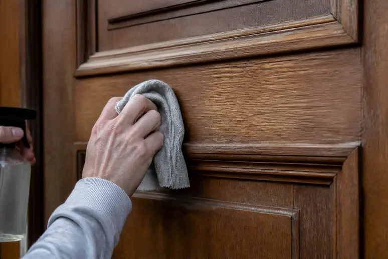 Hände reinigen eine Tür mit einem Anlauger für bessere Lackhaftung.