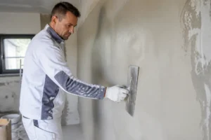 Handwerker glättet eine Wand professionell mit einer Kelle für ein glattes Spachtelergebnis.